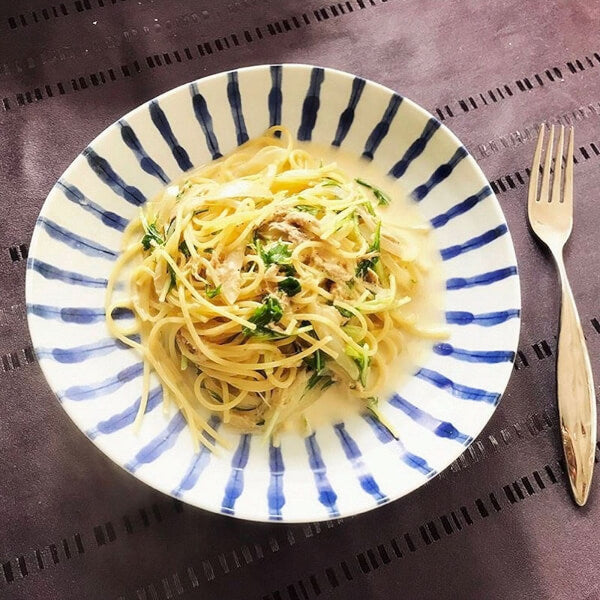 Blue and white striped ceramic plate from Japan, holding a creamy pasta dish with greens.